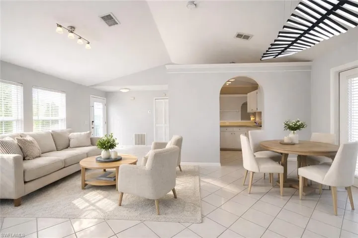 Living room featuring vaulted ceiling, light tile patterned floors, and arched walkways