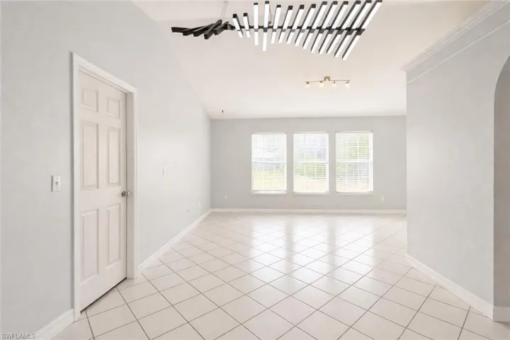 Spare room featuring arched walkways, light tile patterned floors, and vaulted ceiling