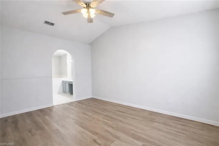 Master_bedroom Empty room featuring lofted ceiling, light wood-style flooring, arched walkways, and a ceiling fan