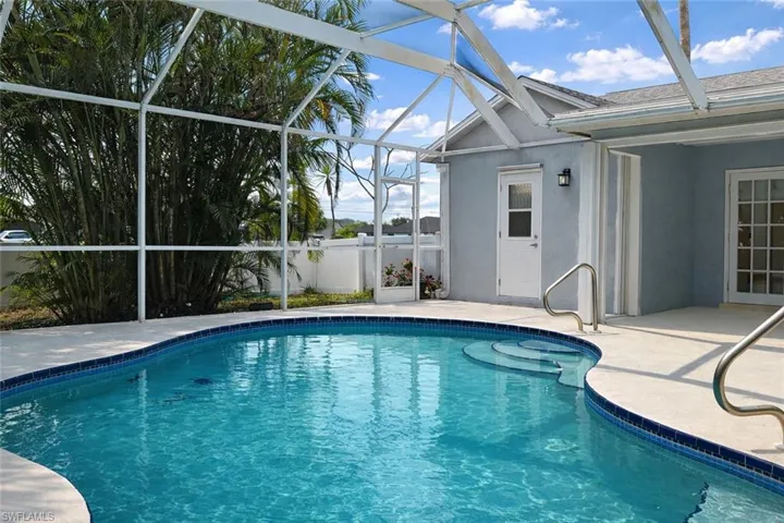 Swimming pool with a patio area, glass enclosure, and a sunroom