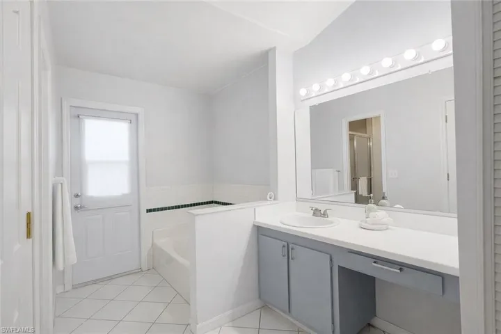 Full bath with a garden tub, vanity, light tile patterned flooring, and a stall shower