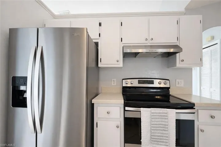 Kitchen featuring stainless steel appliances, under cabinet range hood, and white cabinets
