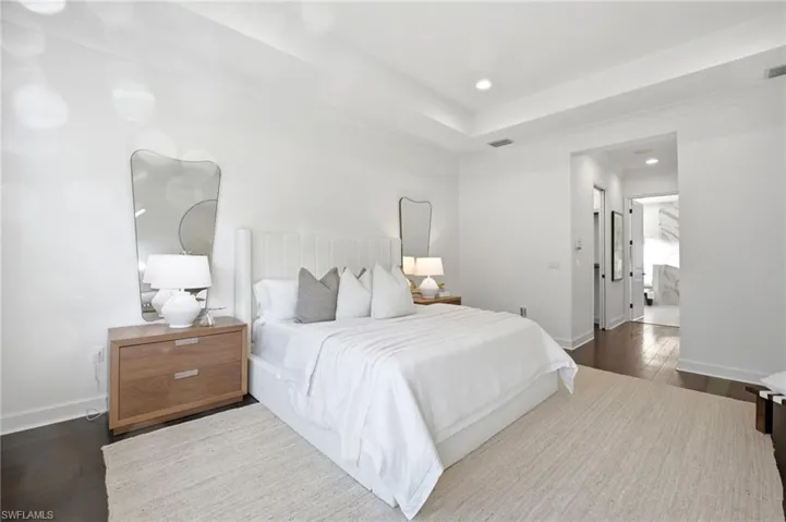 Tray ceiling with recessed lighting, dark wood-finish flooring, and crisp white wall palette