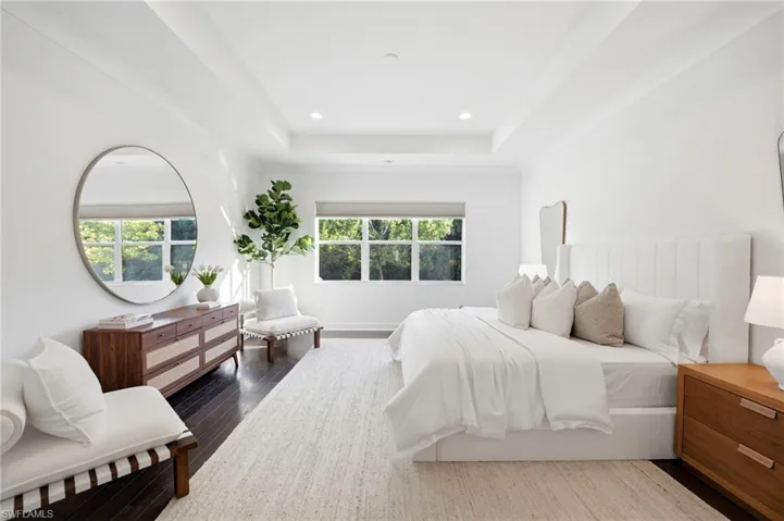 Tray ceiling with recessed lighting, dark wood-finish flooring, and expansive windows