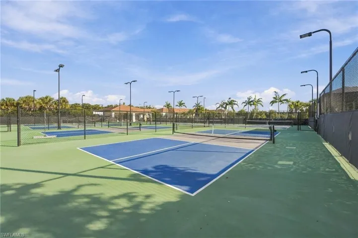 Multi-court athletic facility featuring hard-surfaced playing areas, perimeter chain-link fencing, and overhead court lighting
