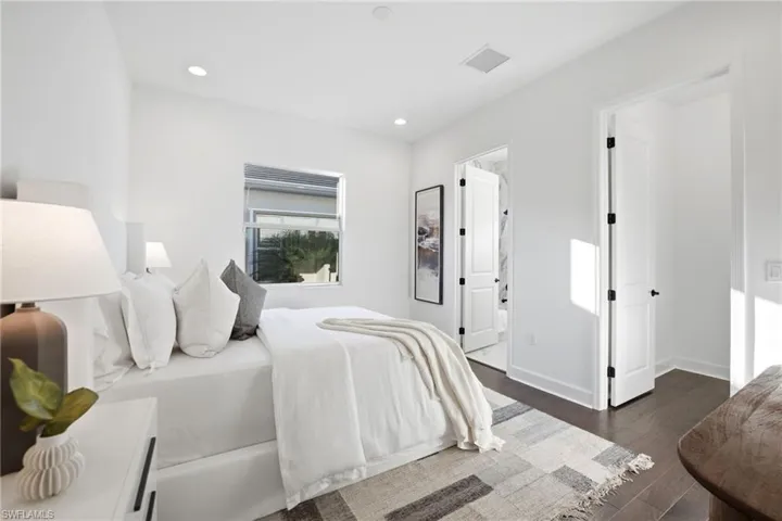 Dark-toned wood-finish flooring, recessed ceiling lighting, single-hung window, and two-panel interior doors with matte black hardware