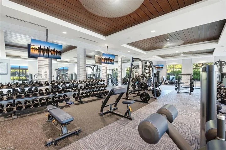 Fitness center featuring a coffered ceiling with wood-finish paneling, mirrored walls, recessed lighting, and large-format tile flooring