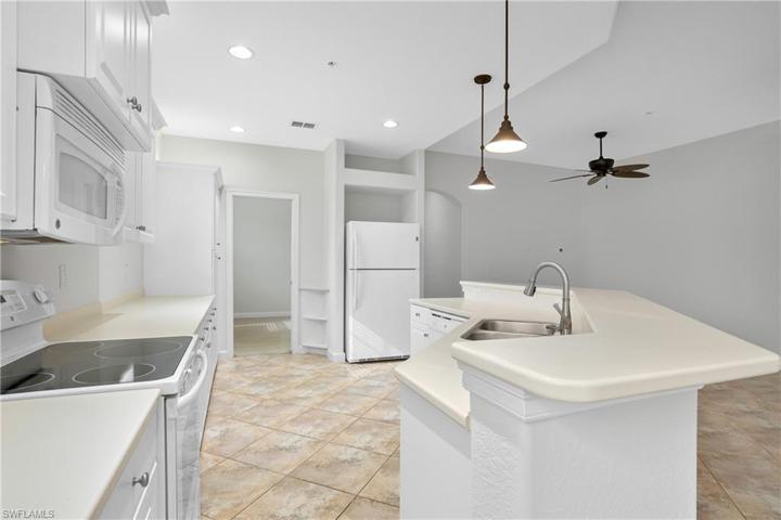 This oversize kitchen boasts plenty of storage space, huge island/breakfast bar, and pendant lighting.