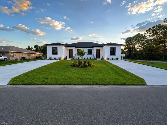 Modern white stucco facade featuring dark-framed windows and a dark roof