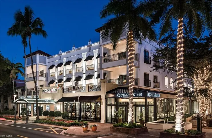 Multi-story commercial building featuring balconies, ground-level retail spaces, and a prominent street-facing entrance with a canopy