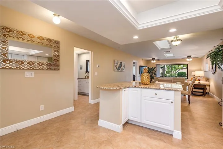 Open-concept living space featuring a tray ceiling, recessed lighting, and skylights