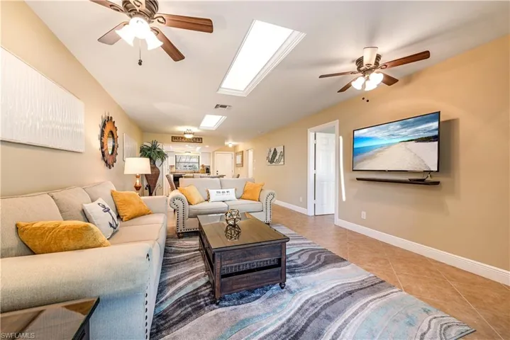 Open concept living area featuring tile flooring, ceiling fans, and skylights