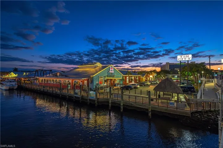 Waterfront commercial structures with illuminated exteriors, an extensive pier, and a thatched-roof gazebo