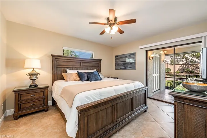 Neutral tone wall finishes, ceiling fan with light fixture, tile flooring, glass sliding door, and a transom window