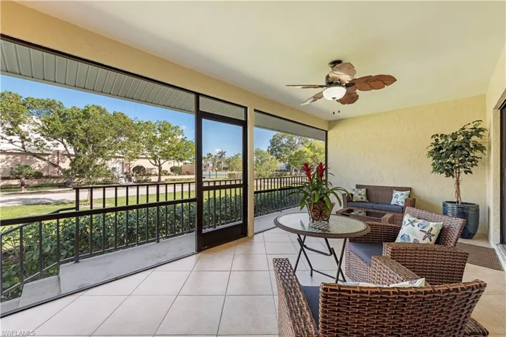 Screened outdoor living space with a ceiling fan, tiled flooring, and a black metal railing
