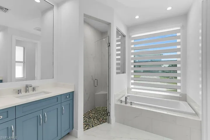 Full bath featuring a marble finish shower, vanity, a garden tub, and recessed lighting