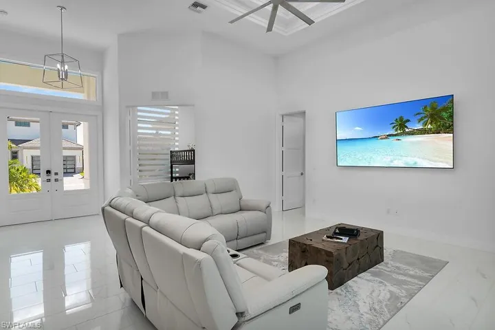 Living room with french doors, light marble finish flooring, a high ceiling, and a ceiling fan