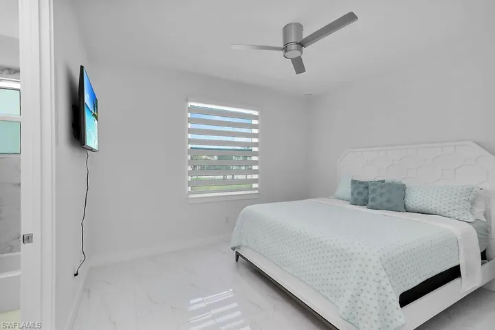 Bedroom #1 with light marble finish floors and a ceiling fan