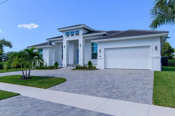 Single story home featuring decorative driveway, a front lawn, stucco siding, and an attached garage