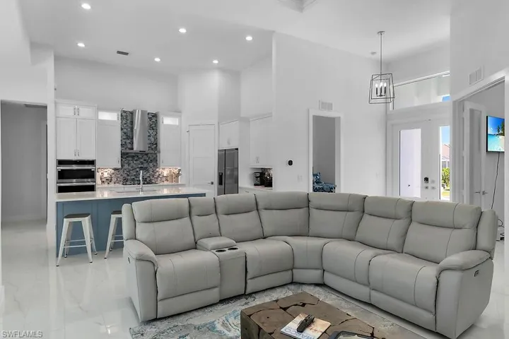 Living room featuring a high ceiling, recessed lighting, and light marble finish flooring