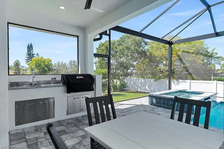 Fenced backyard with an in-ground hot tub, area for grilling, a sunroom, a patio area, and glass enclosure