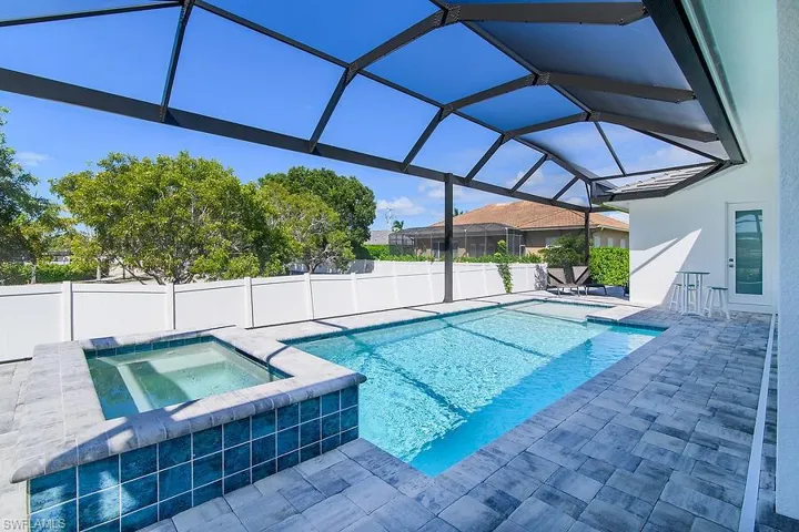 View of pool with a sunroom, a patio, a lanai, a pool with connected hot tub, and a fenced backyard