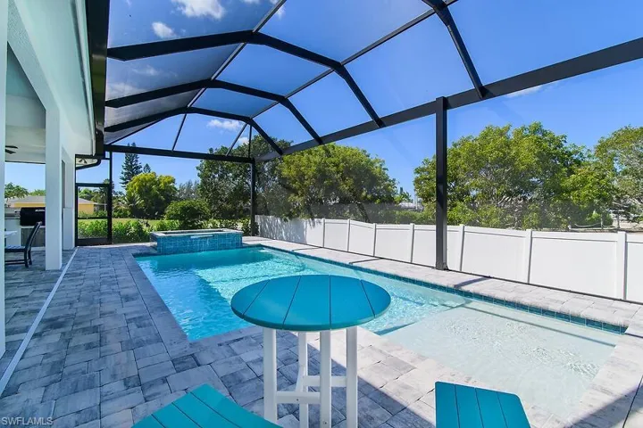 View of pool featuring glass enclosure, a patio area, a pool with connected hot tub, a sunroom, and a fenced backyard
