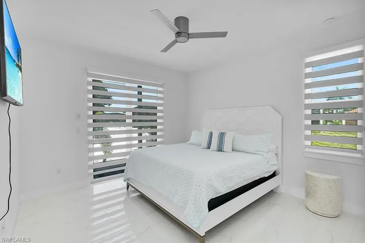 Bedroom #2 with ceiling fan and light marble finish floors