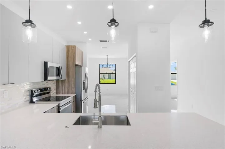 Kitchen featuring pendant lighting, stainless steel appliances, modern cabinets, and light stone counters