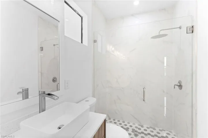 Full bath featuring vanity and a marble finish shower