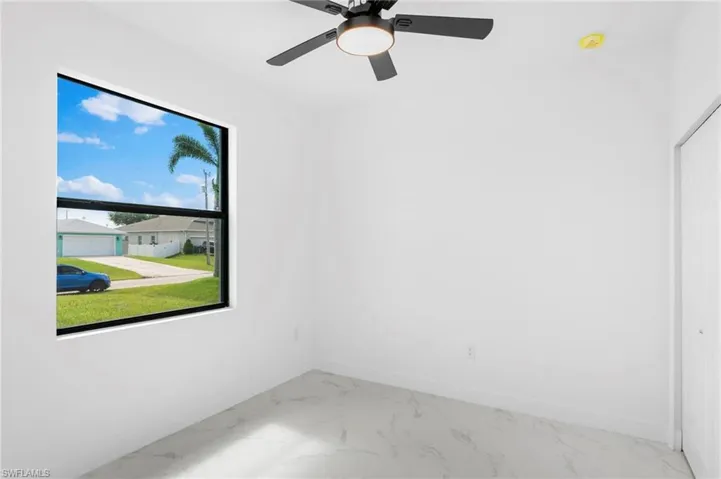 Spare room featuring light marble finish floors and ceiling fan