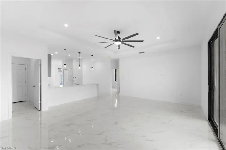 Unfurnished living room featuring recessed lighting, ceiling fan, a raised ceiling, and light marble finish flooring