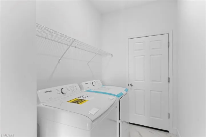 Laundry room with light marble finish floors and washer and clothes dryer