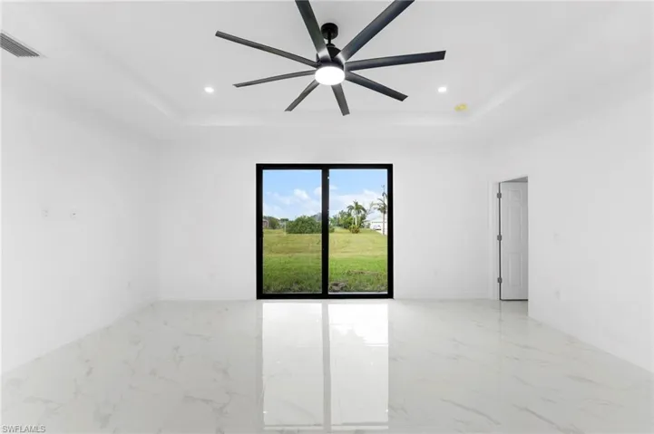 Empty room with light marble finish floors, a raised ceiling, recessed lighting, and ceiling fan