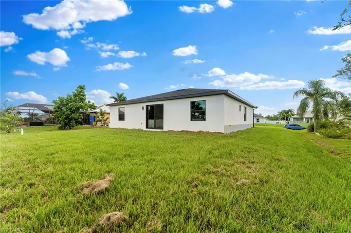 Rear view of house featuring stucco siding and a yard