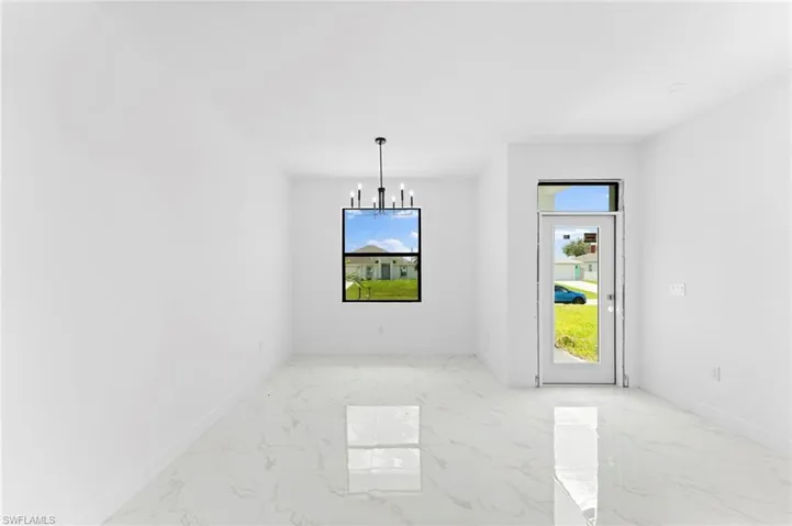 Unfurnished dining area featuring a chandelier and light marble finish floors