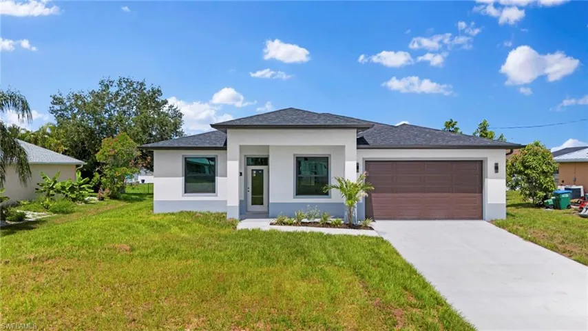 Prairie-style house featuring a front yard, stucco siding, concrete driveway, and an attached garage