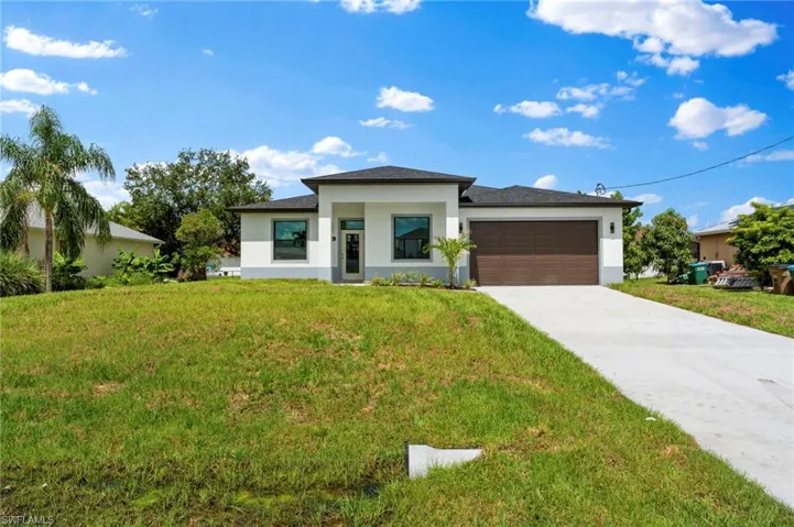 Prairie-style home featuring a front yard, stucco siding, concrete driveway, and a garage