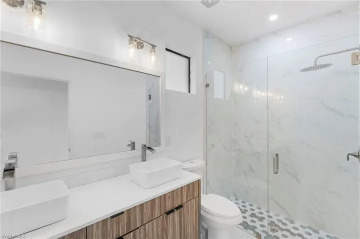 Bathroom with double vanity and a marble finish shower