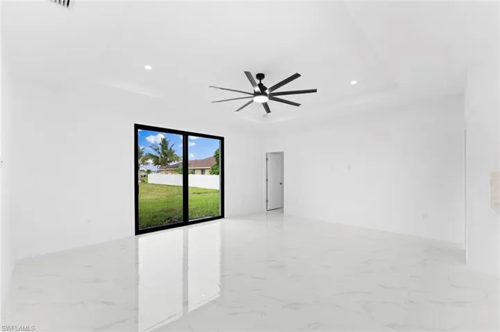 Empty room featuring light marble finish floors, ceiling fan, and recessed lighting
