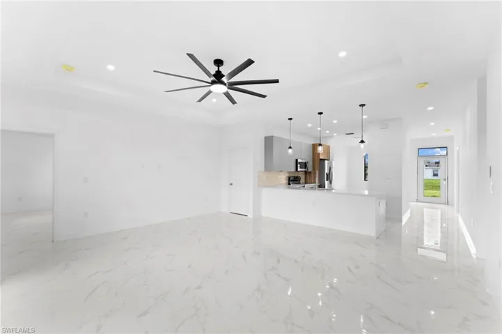 Unfurnished living room with a tray ceiling, recessed lighting, and ceiling fan