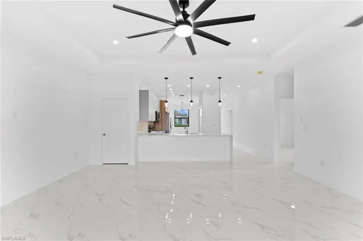 Unfurnished living room featuring a raised ceiling, recessed lighting, and ceiling fan