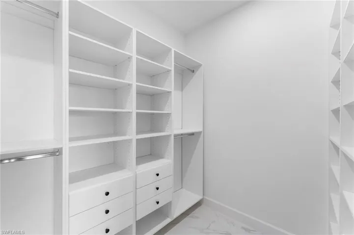Walk in closet featuring light marble finish flooring