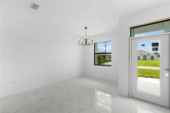 Unfurnished dining area featuring light marble finish flooring and a chandelier