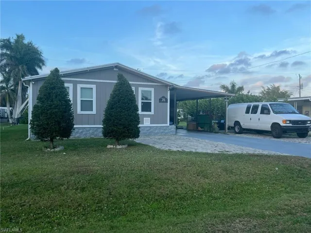 View of front of property with a front yard, driveway, and an attached carport