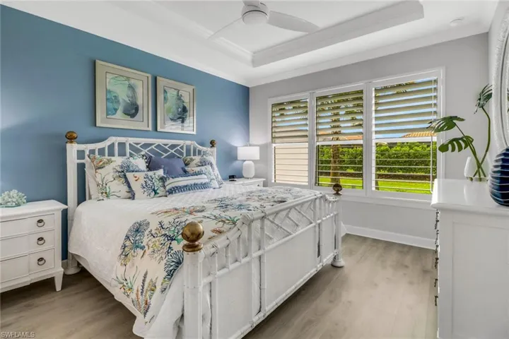 Bedroom featuring ornamental molding, light wood-type flooring, baseboards, and a ceiling fan