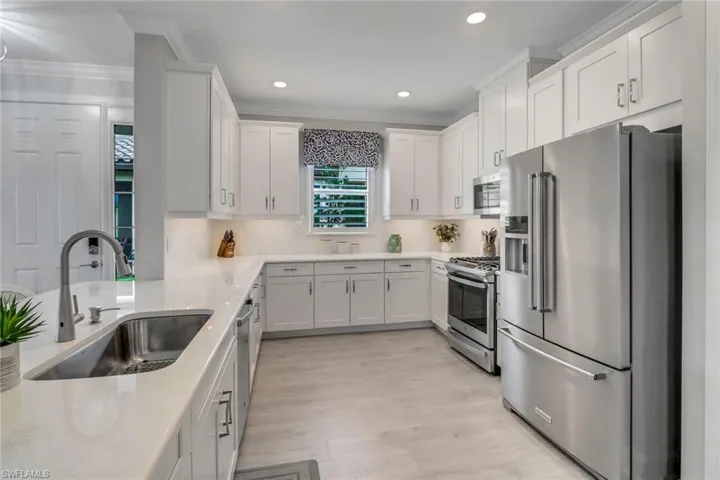 Kitchen featuring a sink, white cabinets, appliances with stainless steel finishes, decorative backsplash, and crown molding