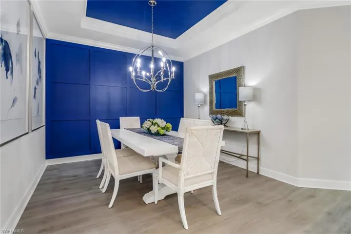 Dining area featuring crown molding, a tray ceiling, a notable chandelier, and wood finished floors