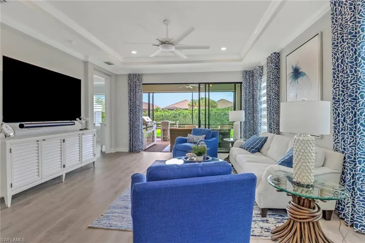 Living room with ceiling fan, light wood-style flooring, recessed lighting, ornamental molding, and a raised ceiling