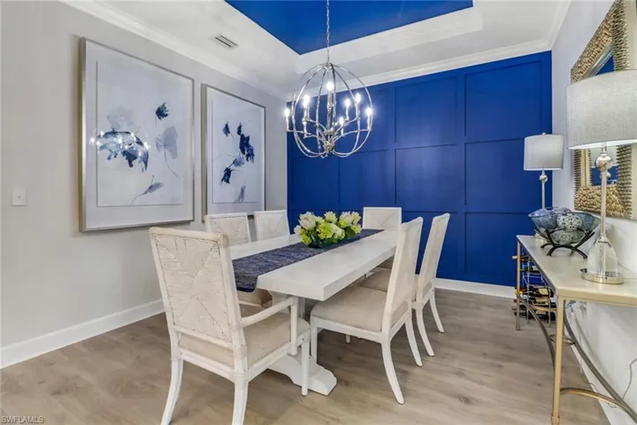 Dining area with a chandelier, a tray ceiling, and feature wall